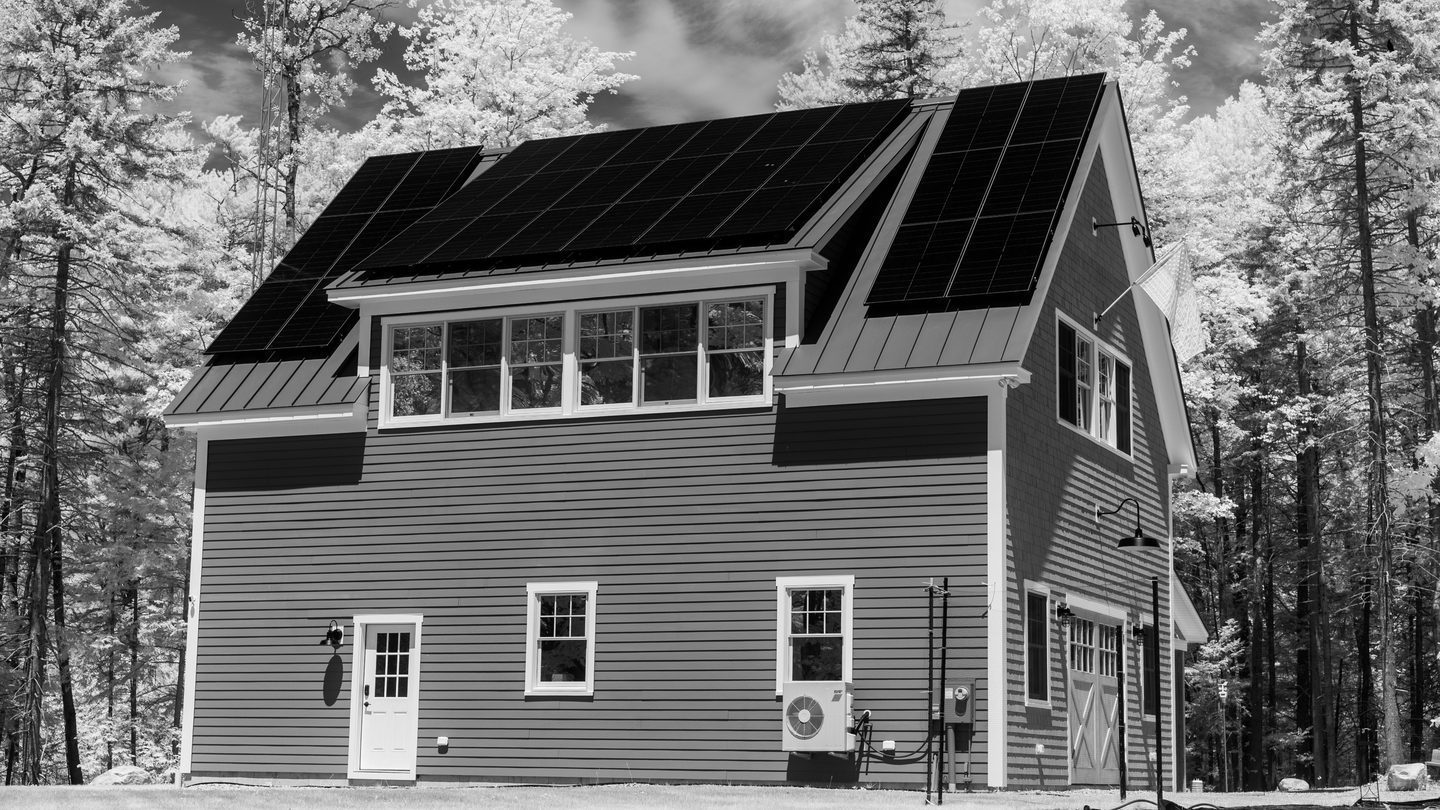 Home with rooftop solar panels surrounded by trees