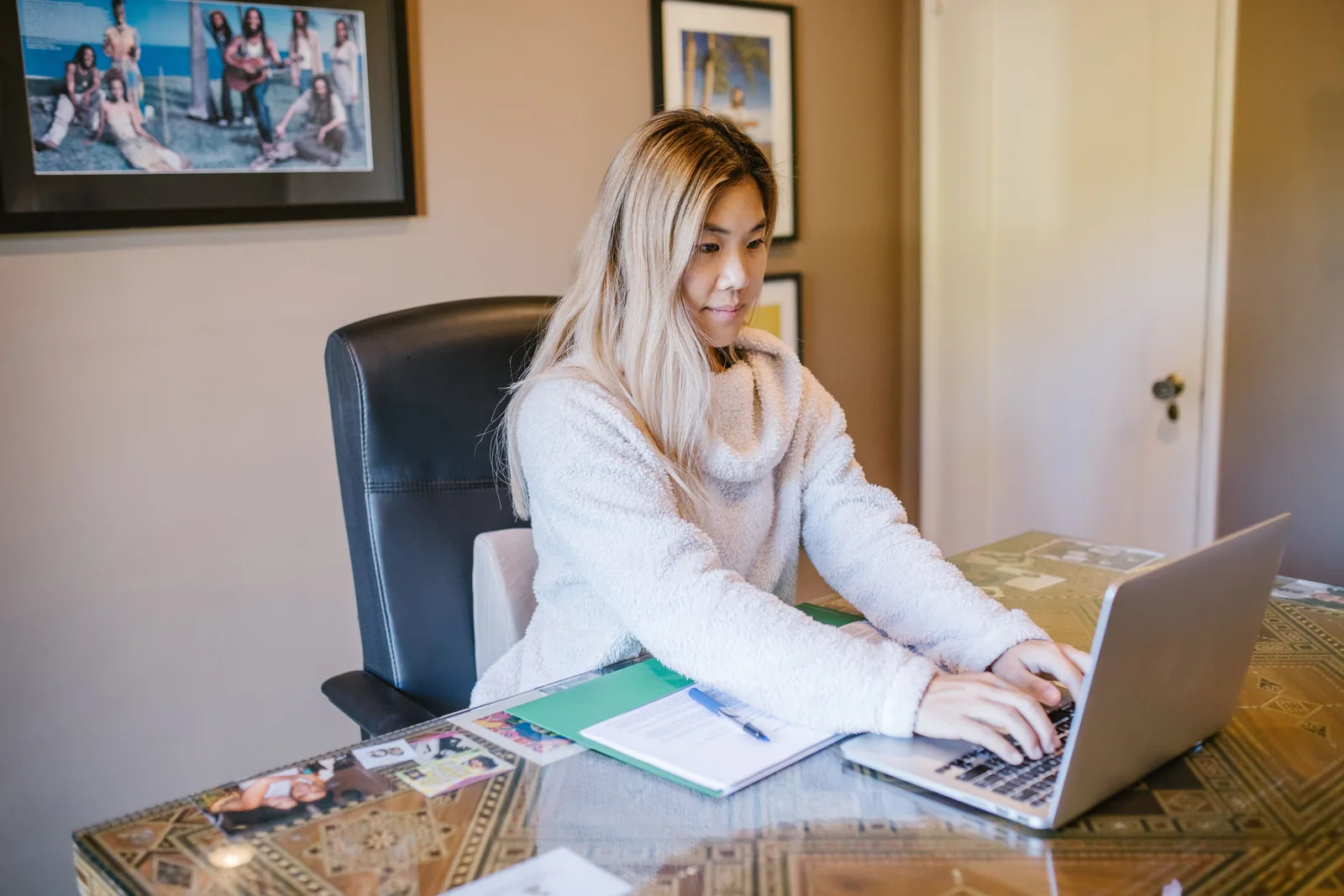 Woman working on a laptop with notes at a home desk